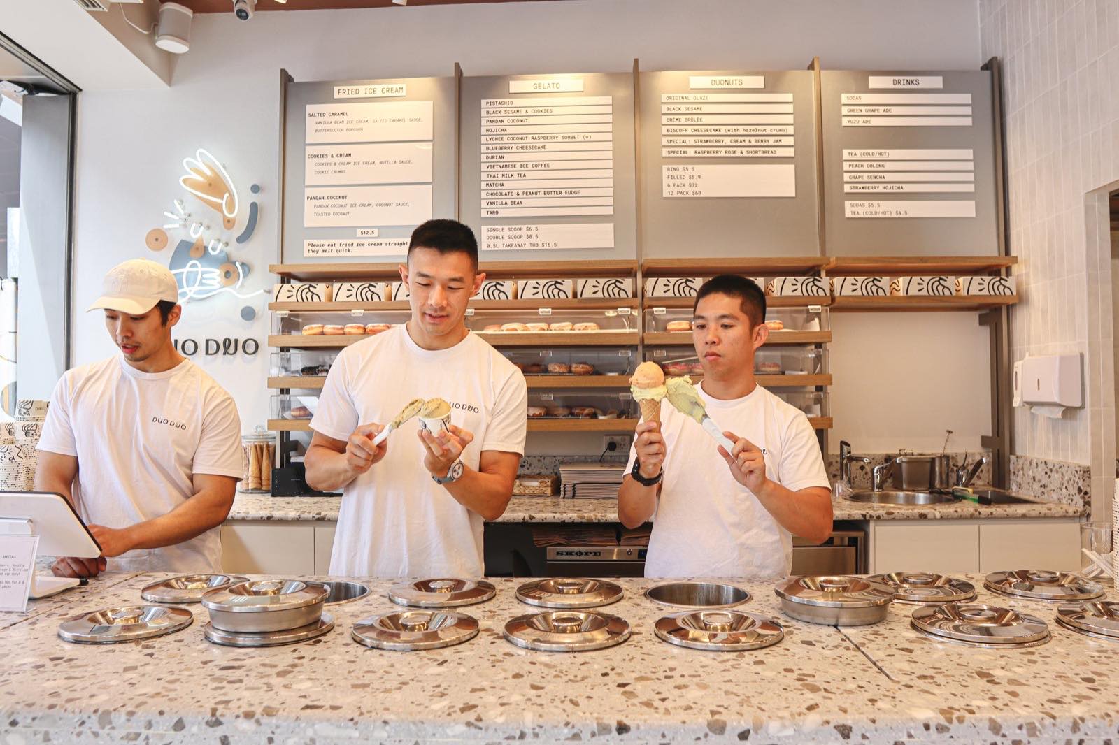 Three Duo Duo staff scooping from the lidded steel pozzetti along the terrazzo counter at Strathfield.