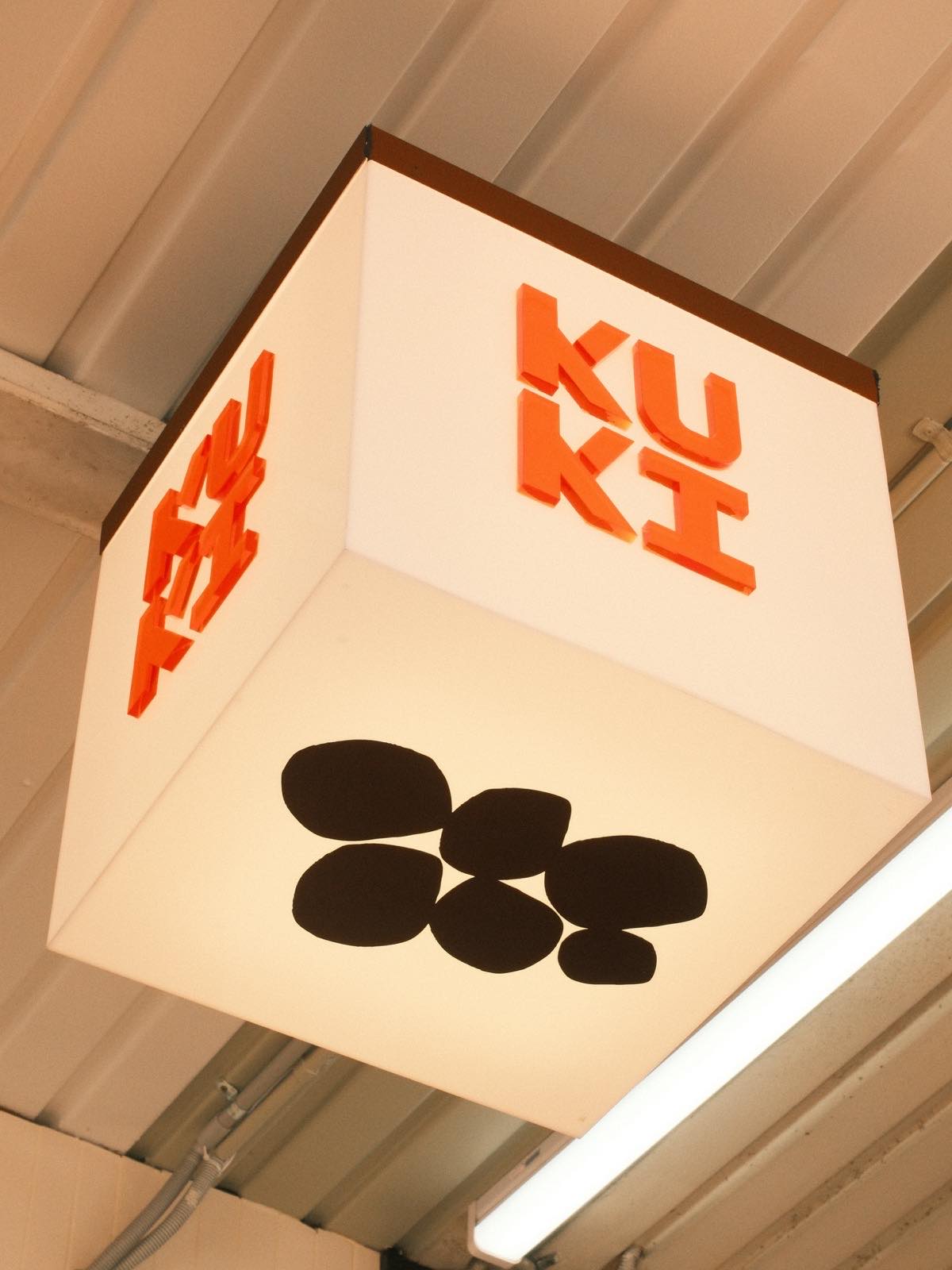 KUKI's light-box sign: orange KUKI lettering above a black cluster of rounded shapes.